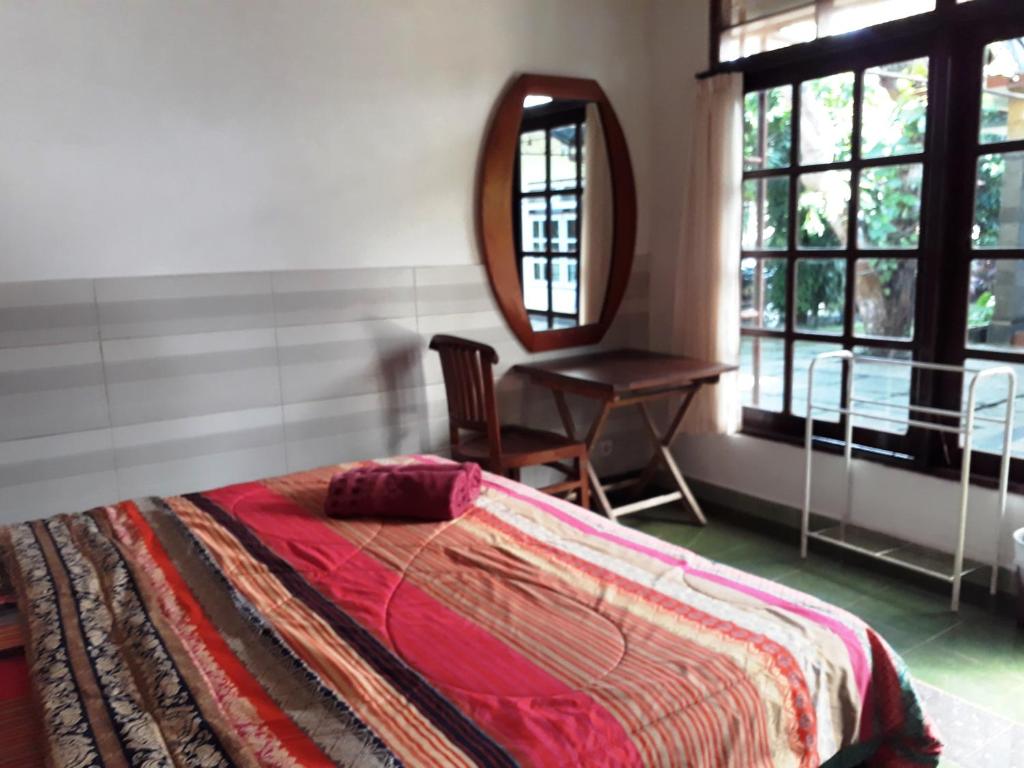 努沙杜瓦Manuh Guest House的一间卧室配有一张床、镜子和椅子