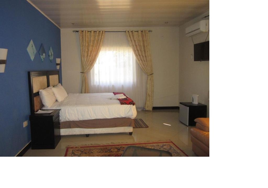 利文斯顿Royal Olympia Lodges and Safaris Livingstone的一间卧室设有一张床和一个窗口