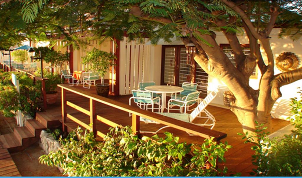 棕榈滩阿鲁巴岛海滩别墅酒店的门廊配有桌椅和一棵树