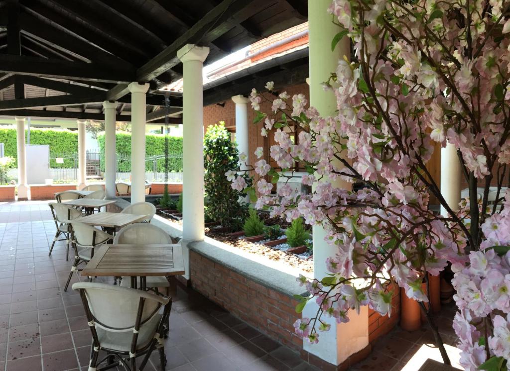 下麦克加诺Ostello Casa Emmaus的庭院配有桌椅和粉红色的鲜花