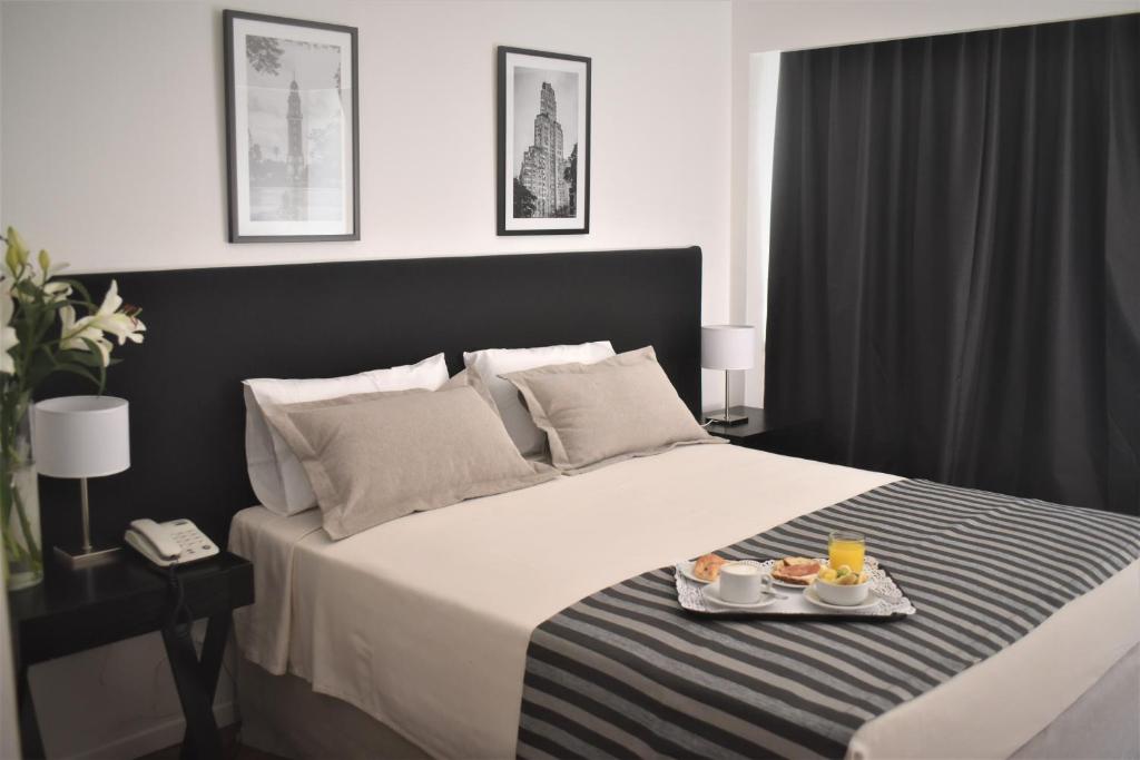 布宜诺斯艾利斯格朗德国王酒店的一间卧室,配有一张带两盘食物的床