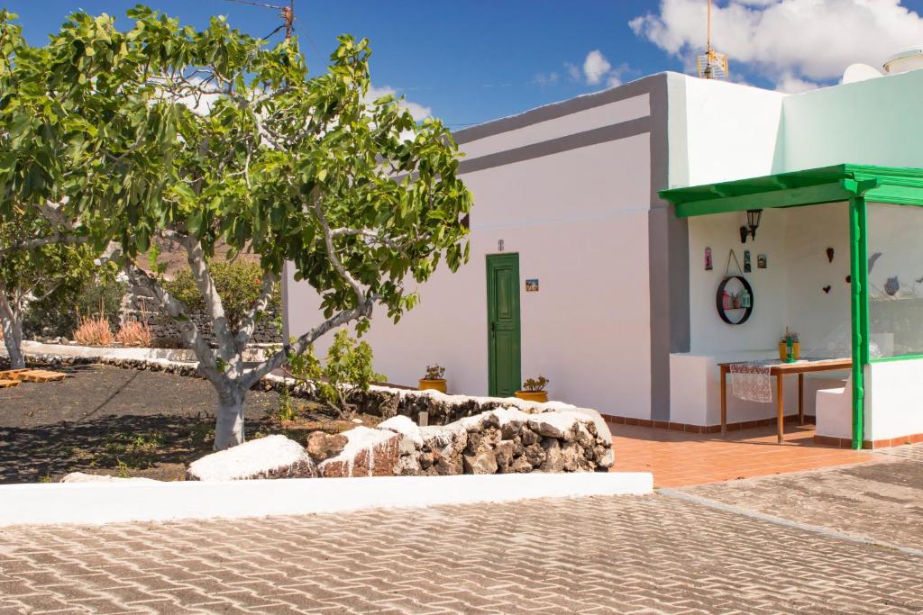 MalaCasa Mi Tio Perico的白色的建筑,有绿门和一棵树