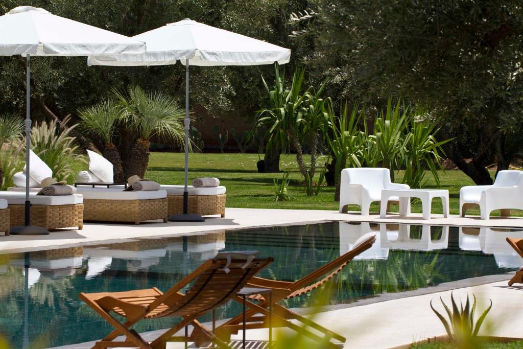 Douar Caïd LayadiHotel Les Cinq Djellabas的游泳池旁的游泳池配有椅子和遮阳伞