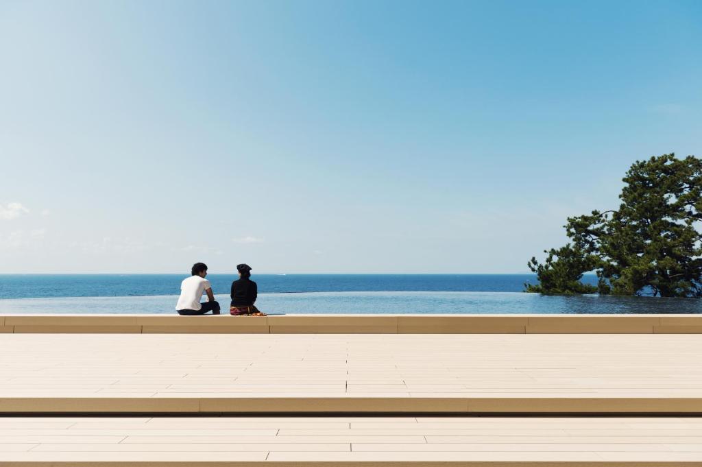 白滨白浜奇特莱斯希莫尔酒店的两个人坐在长凳上,看着大海