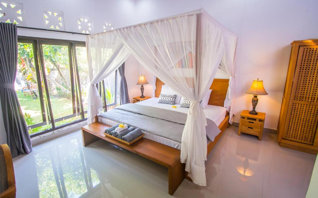 特贾库拉Gede House Tejakula的一间卧室设有天蓬床和窗户。