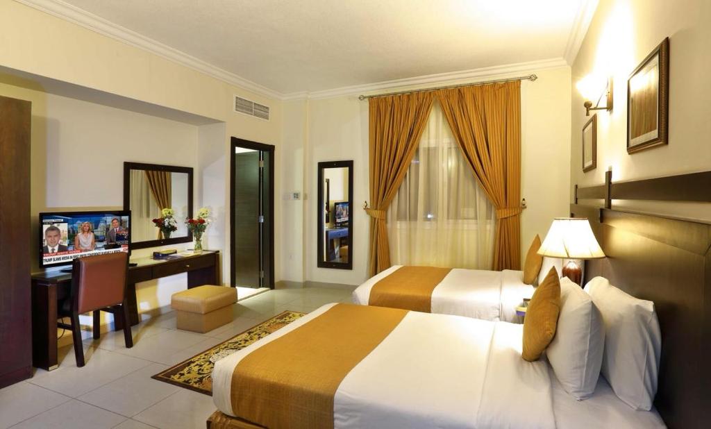 沙迦阿尔哈亚特套房酒店的酒店客房配有两张床和一张书桌