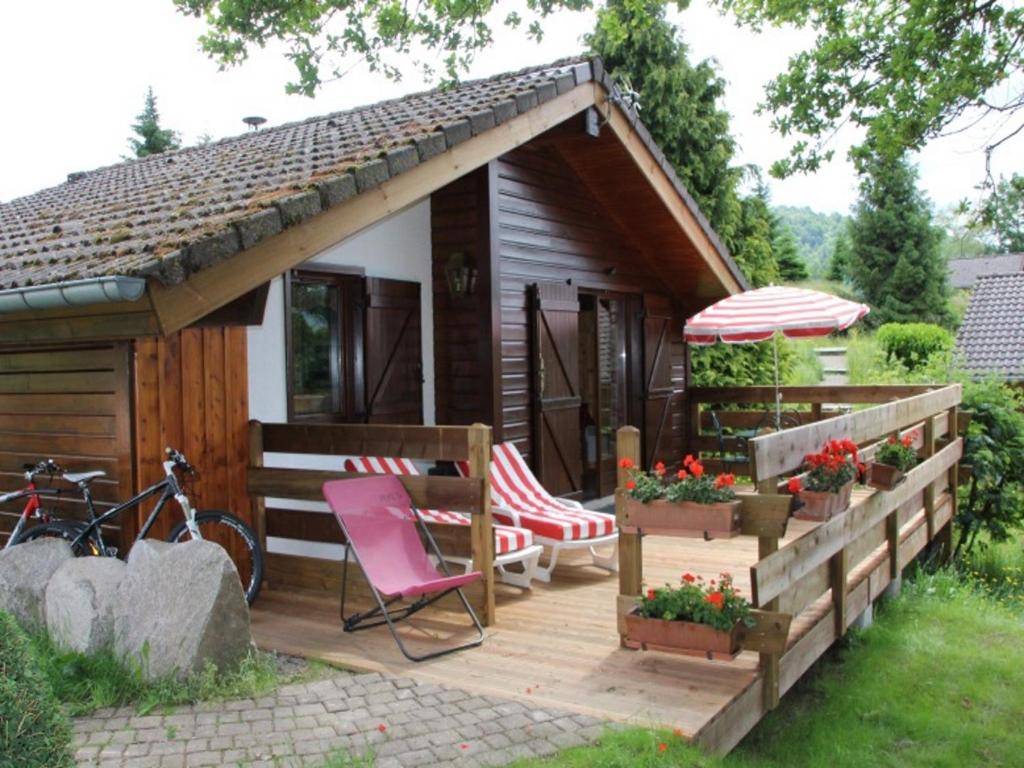 勒蒂约Nice chalet with dishwasher, in the High Vosges的小屋设有1个带椅子和遮阳伞的甲板