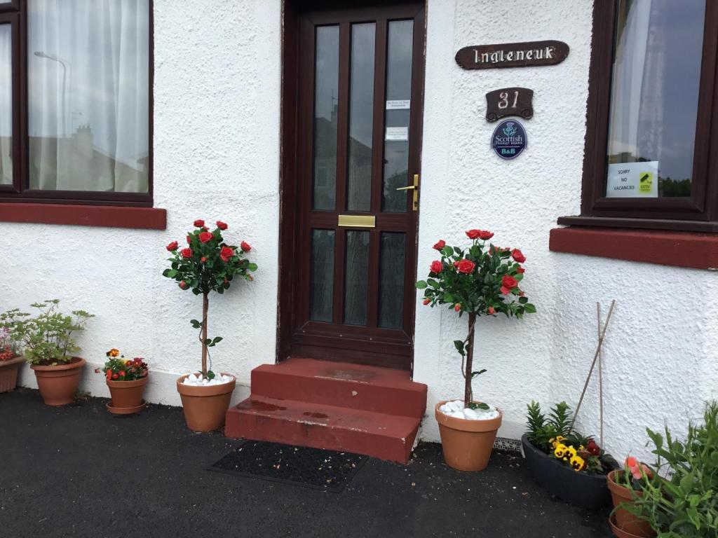 爱丁堡Ingleneuk Bed and Breakfast的前面有盆栽植物的房子的门