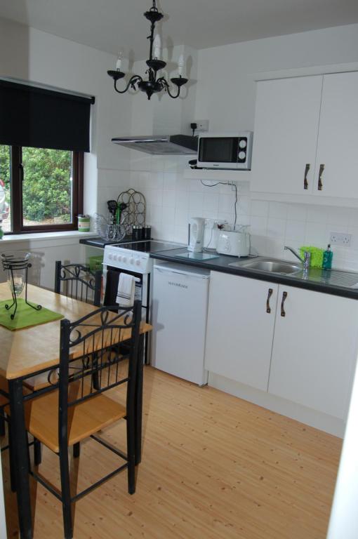基拉尼Inisfail的厨房配有白色橱柜和木桌