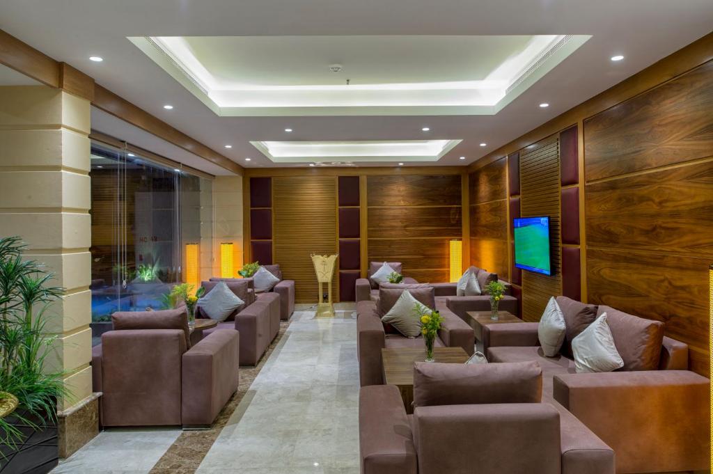 吉达Classical Hotel Suites的一间设有棕色皮椅和电视的等候室