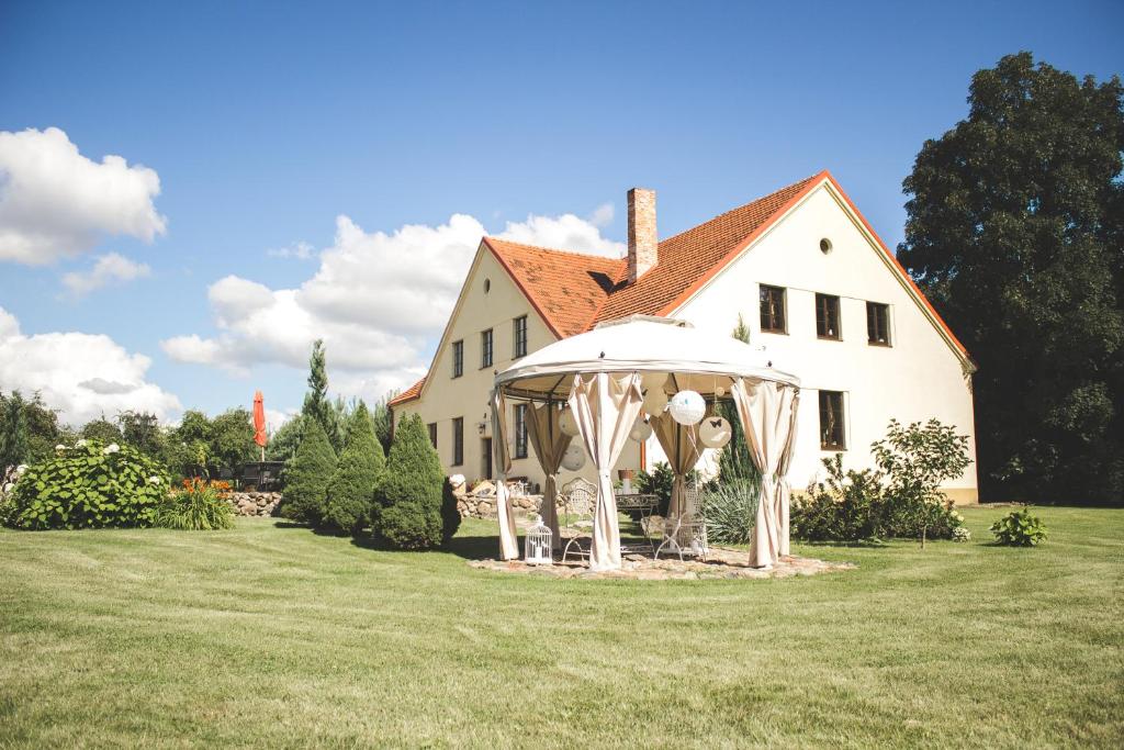 AkmeniaiAkmenių Dvaras的院子里的白色房子,配有遮阳伞和椅子