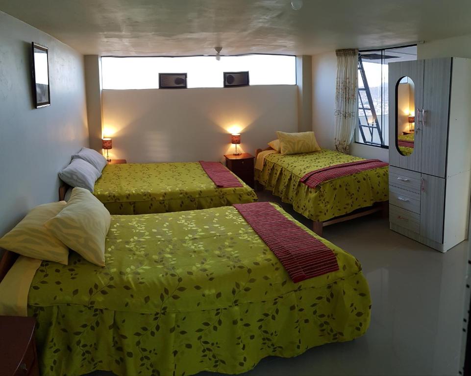 库斯科Feliz Vista Casa-Hospedaje的酒店客房带两张带黄床单的床