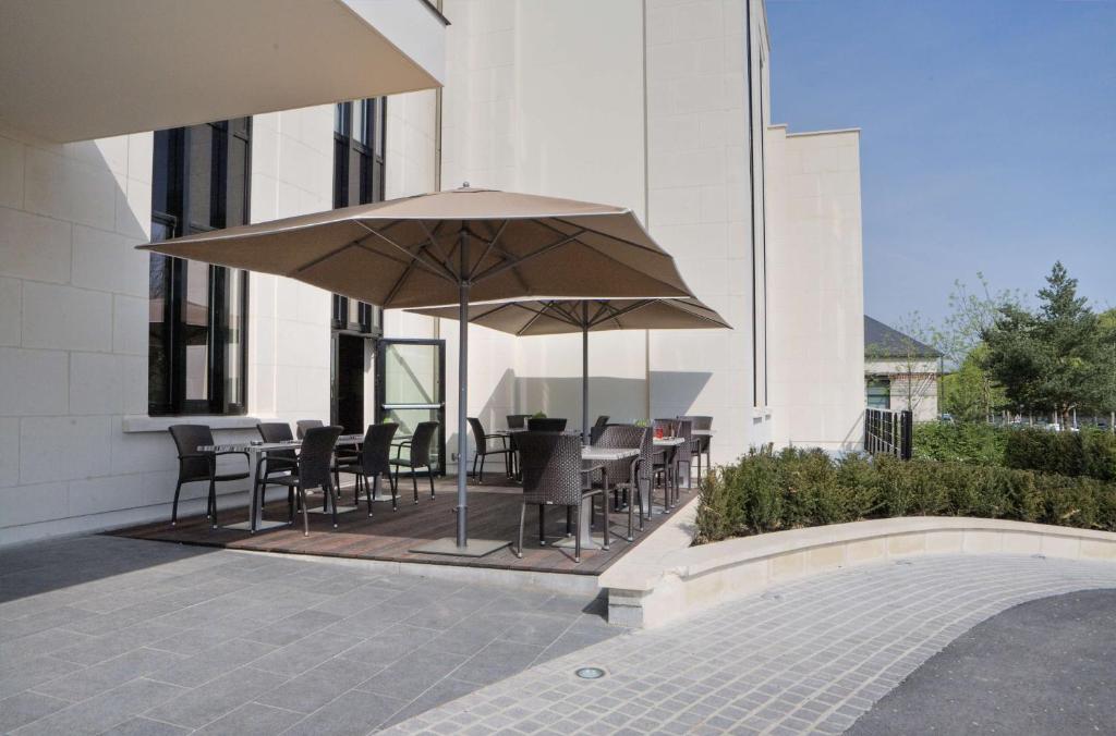 苏瓦松贝斯特韦斯特弗兰克升级酒店的一个带桌椅和遮阳伞的庭院