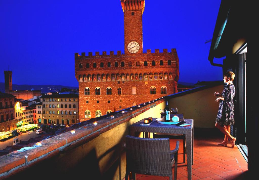 佛罗伦萨瑞雷斯广场酒店的站在带钟楼的阳台顶上的女人