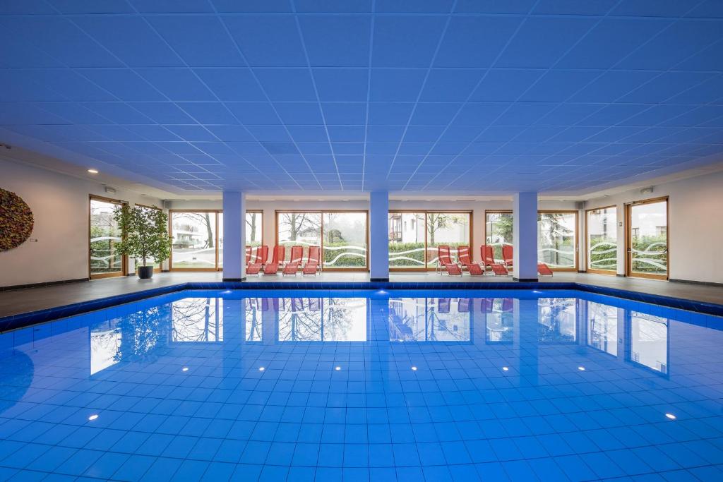 卡尔达罗马萨池酒店的大型游泳池设有蓝色瓷砖地板和窗户。