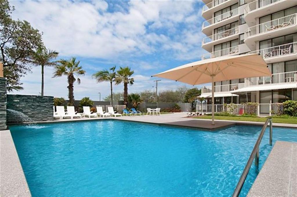 黄金海岸林荫大道塔楼酒店的一座带遮阳伞的游泳池位于大楼旁