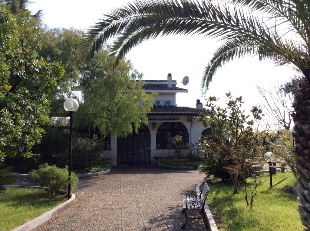 孔韦尔萨诺Paradiso in campagna的公园里棕榈树和长椅的房子