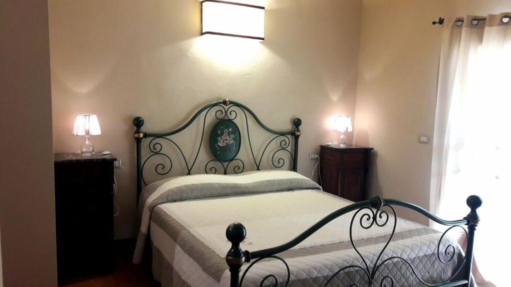 圣吉米纳诺La Tenuta di Castelvecchio的一间卧室配有一张床、两盏灯和一个窗户。