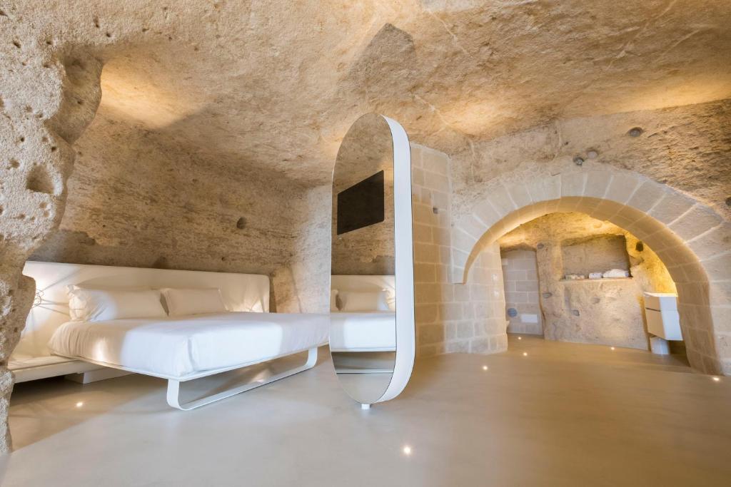 马泰拉Aquatio Cave Luxury Hotel & SPA的石墙客房的卧室配有一张床