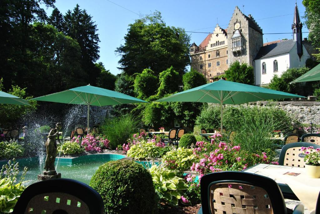 贝尔恩里德Schloss Egg的一个带喷泉和绿色遮阳伞的花园