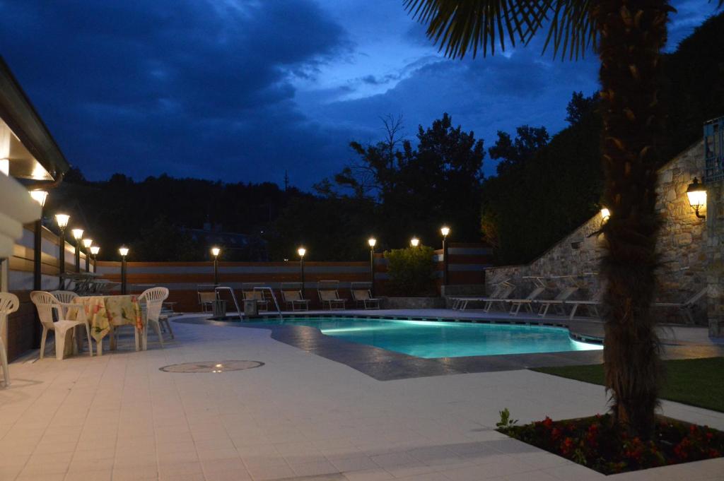 塔皮安诺普拉扎酒店的游泳池在晚上配有桌椅