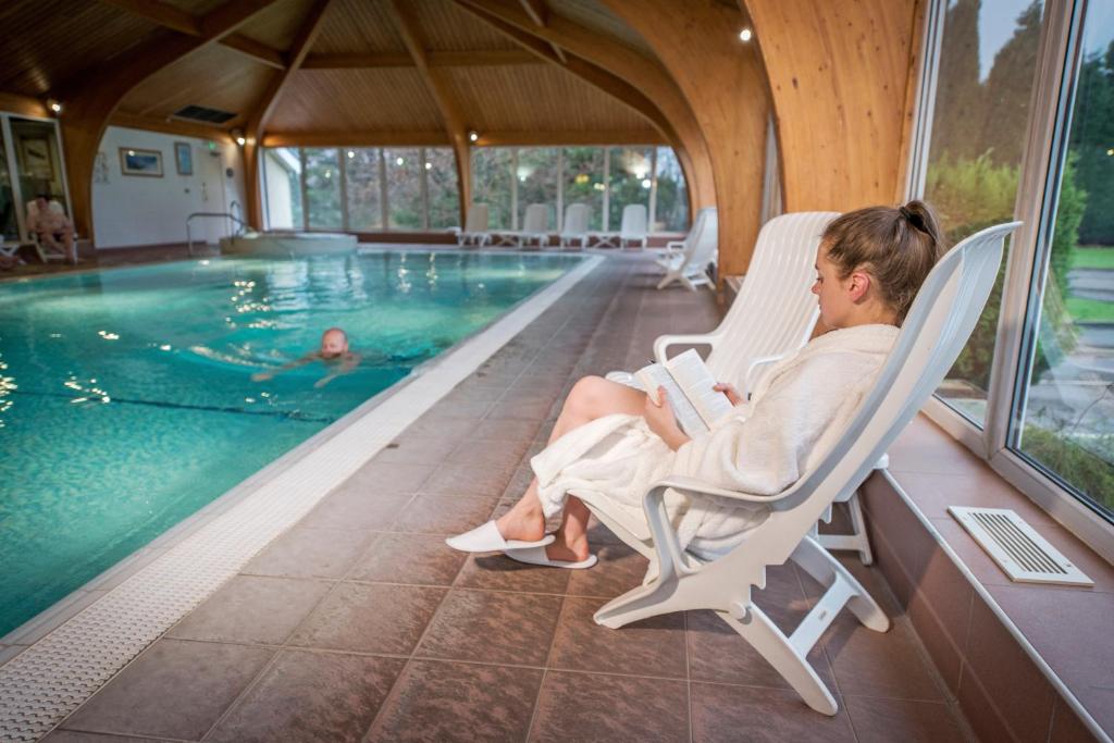 威廉堡斯特拉斯莫尔本尼维斯酒店&休闲俱乐部的坐在游泳池旁椅子上的女人