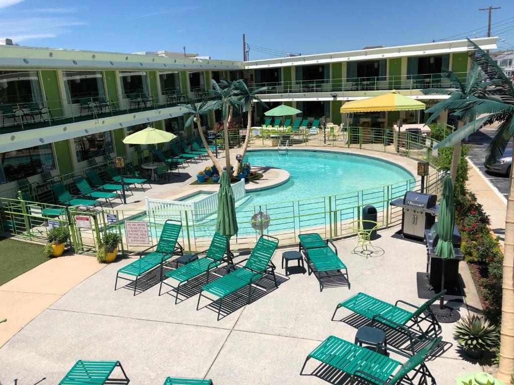 威尔伍德克拉斯特加勒比汽车旅馆的一座带绿椅和遮阳伞的游泳池