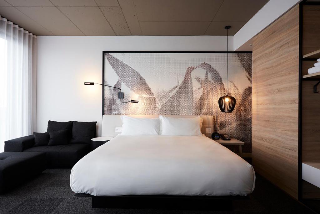 布罗瑟德Hôtel Escad Quartier DIX30的卧室配有一张白色的大床和一张沙发。