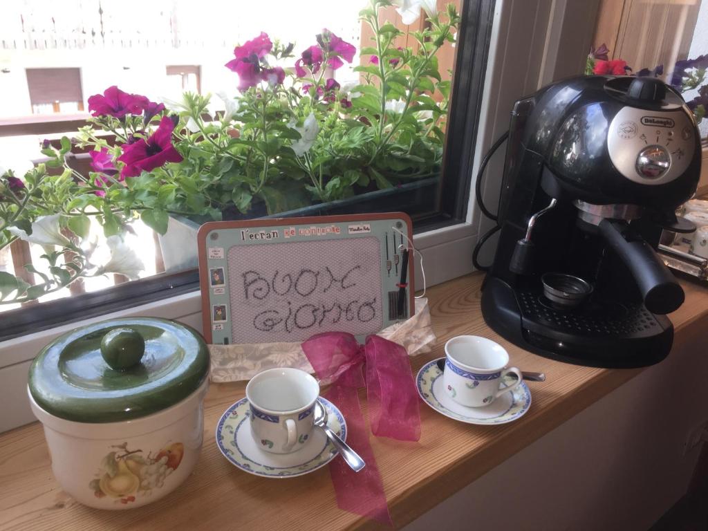 费拉迪普利米罗b&b Casa Tavernaro的一张桌子,上面有2杯,咖啡壶和标志