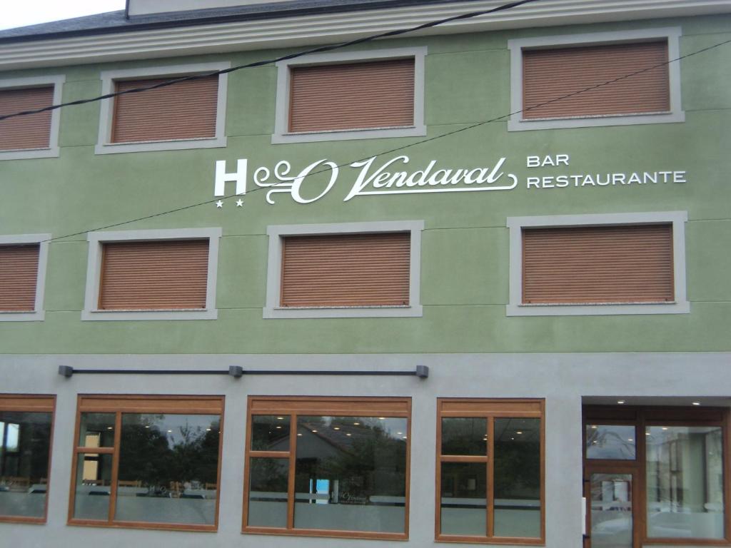 巴雷罗斯O Vendaval Hostal Restaurante的绿色建筑的侧面有标志