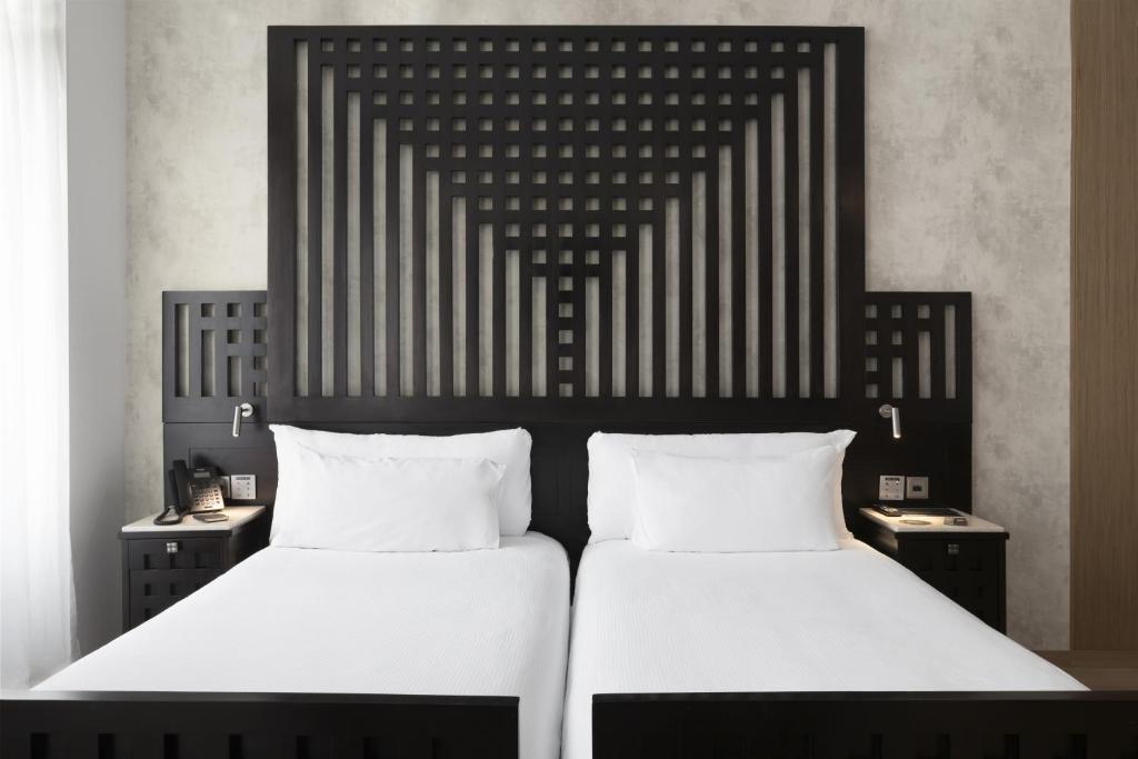 马德里ICON Casona 1900的一间卧室配有两张带白色床单的床