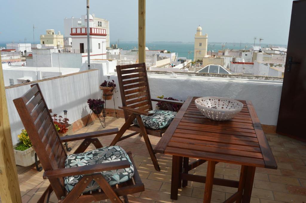 加的斯Apartamento El Mirador de Cadiz的阳台配有一张木桌和椅子,阳台设有灯塔
