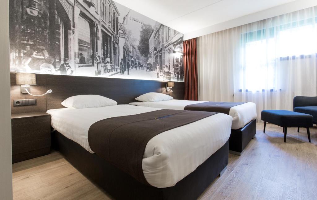 布森布森希尔弗瑟姆堡垒酒店的酒店客房设有两张床,墙上挂有绘画作品