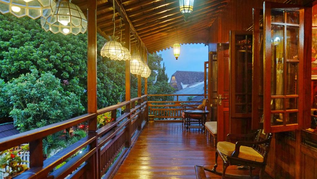 万隆Badjoeri Ethnic Wooden Homestay的阳台,餐厅配有椅子和灯