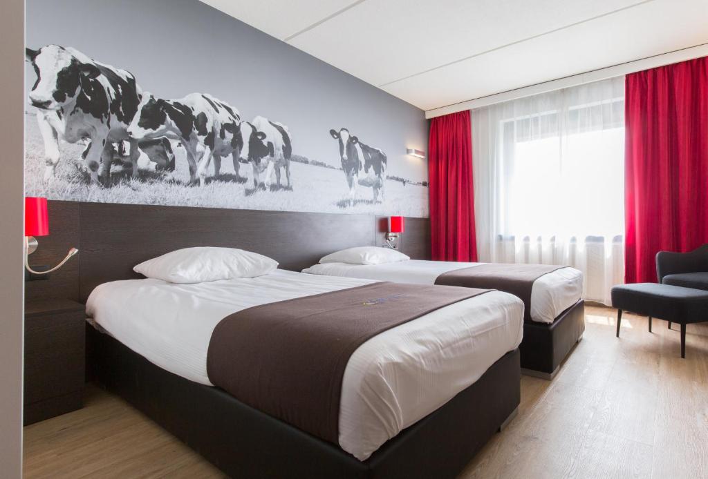 阿尔梅勒阿尔梅勒酒店的配有红色窗帘的酒店客房的两张床