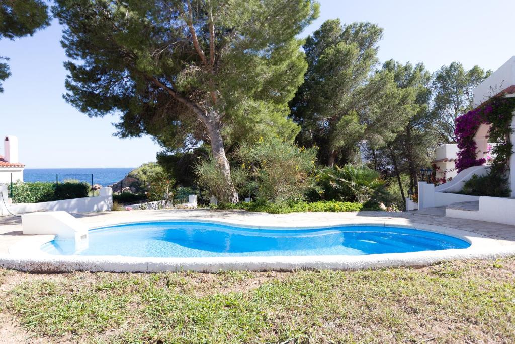 拉梅特拉·德·玛尔INNOUTHOME Casa Piscina的一座位于庭院的游泳池,花园内种有树木,海洋环绕