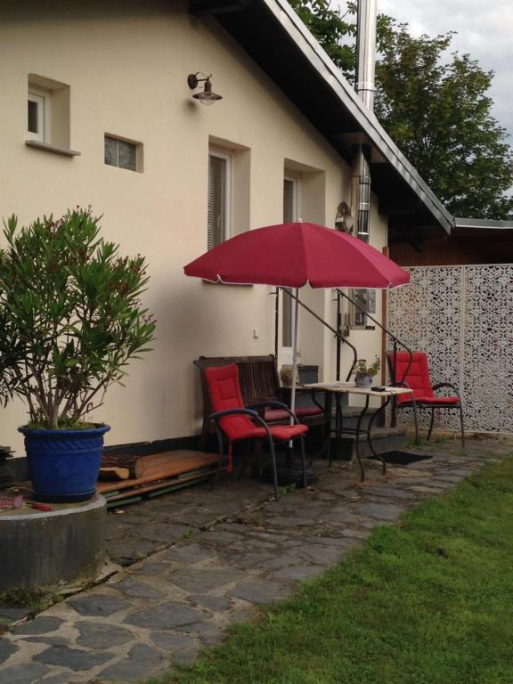 上韦瑟尔Künstlerhäuschen的庭院配有桌椅和红色遮阳伞。