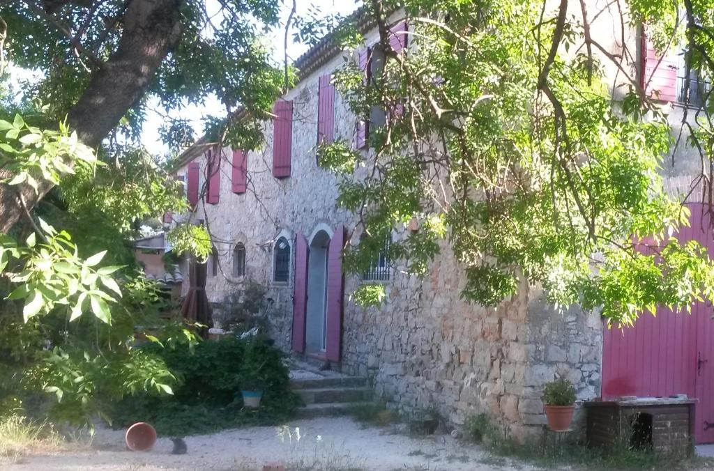 滨海拉塞讷Joli T2 RDC ancienne bergerie的一座古老的石头房子,拥有粉红色的门和树木