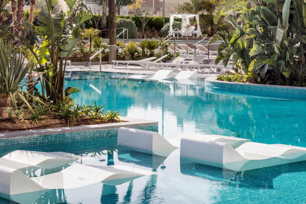 马尔格莱特德玛AQUA Hotel Silhouette & Spa - Adults Only的一个带白色椅子和蓝色水的游泳池
