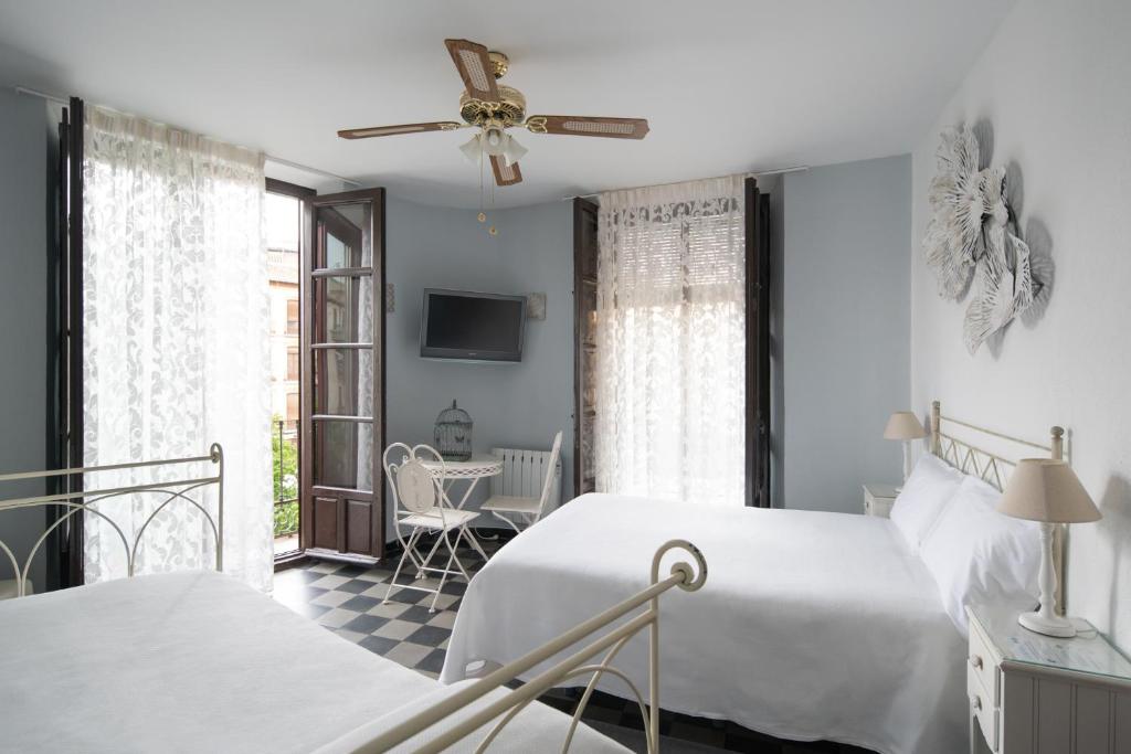 格拉纳达Pension Venecia Gomerez的一间白色卧室,配有两张床和电视