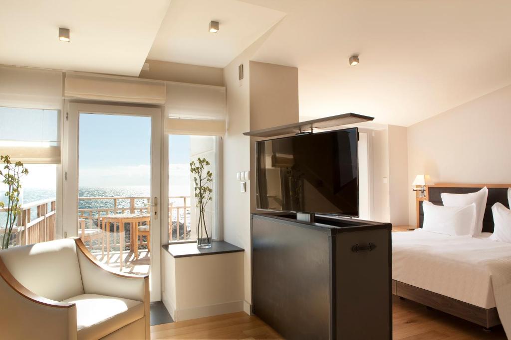勒克鲁西克的奥欧深格兰德酒店的一间卧室配有一张床、一台电视和一个阳台
