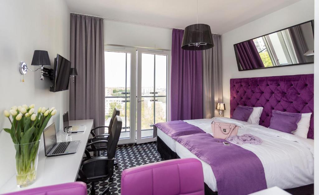 华沙Apartamenty Vola Residence的酒店客房配有紫色的床和书桌
