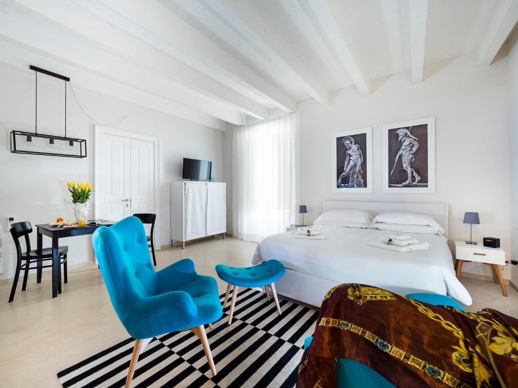 锡拉库扎Re Federico Boutique Hotel的白色卧室配有蓝色椅子和一张床