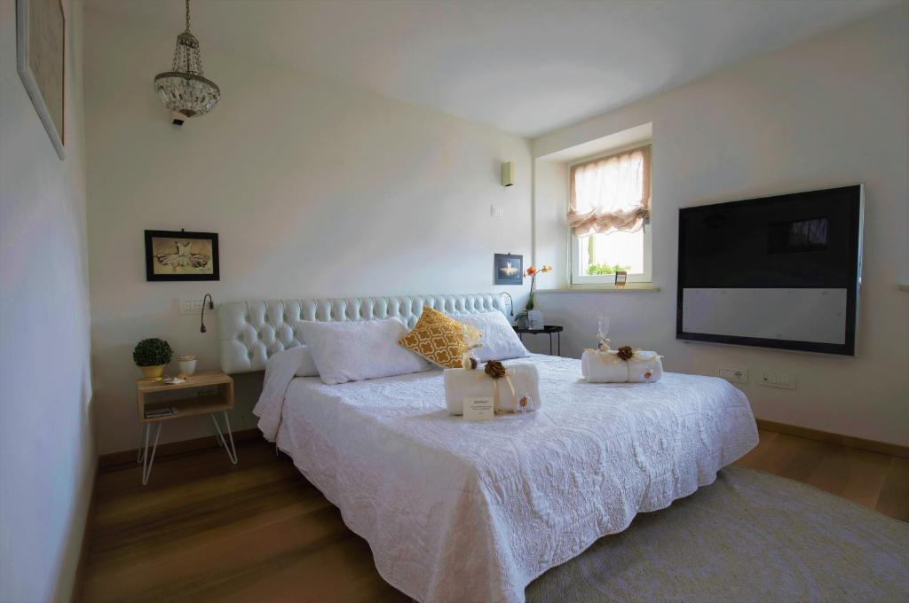 维罗纳卡萨民宿的卧室配有白色的床和平面电视。