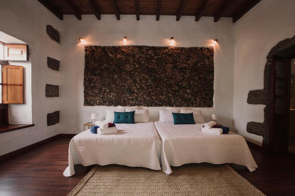 蒂纳霍Hotelito Rural Flor de Timanfaya的一间卧室设有两张床,墙上挂着一幅画