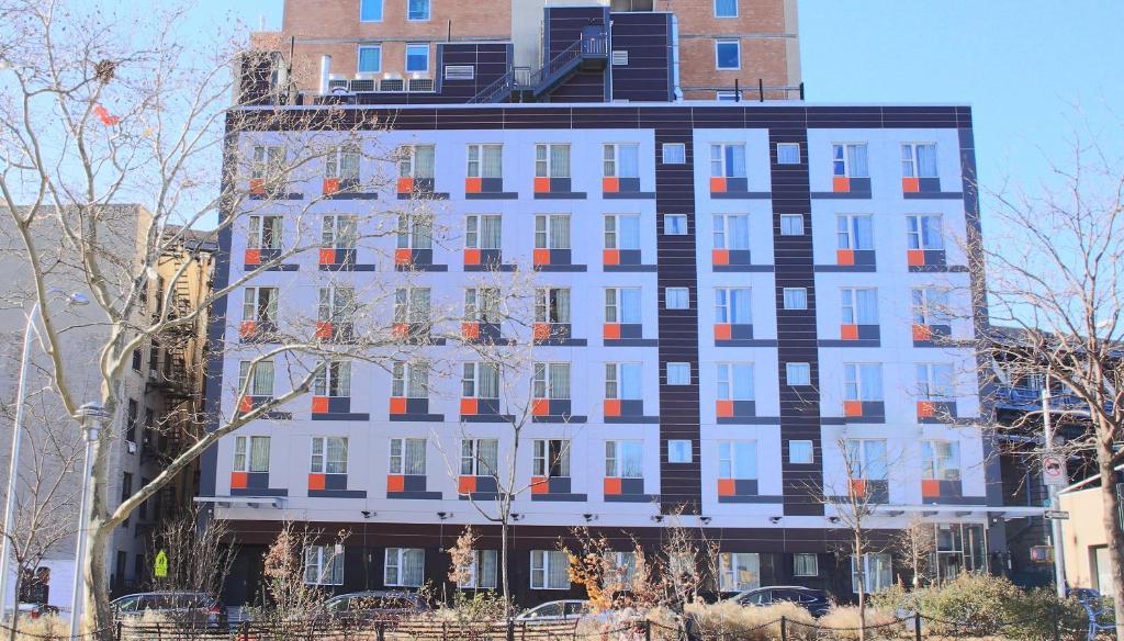 纽约麦迪逊LES酒店的一座高大的白色建筑,拥有橙色和黑色的窗户