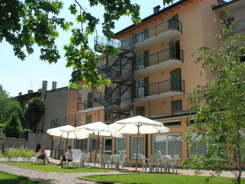 罗韦雷托Ostello Città di Rovereto的前面有桌子和伞的建筑