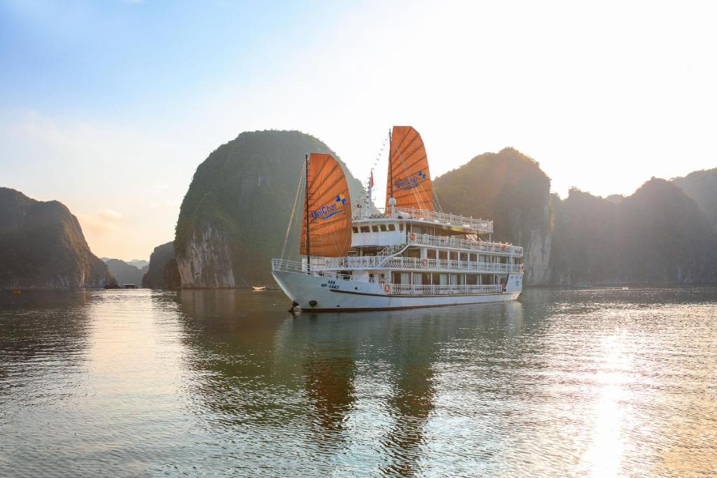 下龙湾UniCharm Cruise的一艘在水中装有橘子帆的游轮