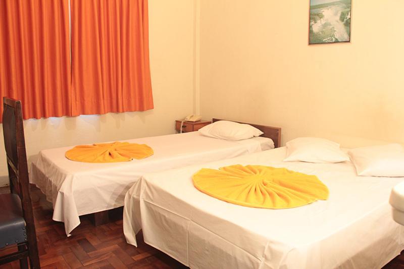 马林加Hotel Indaiá的橙色窗帘间内的两张床