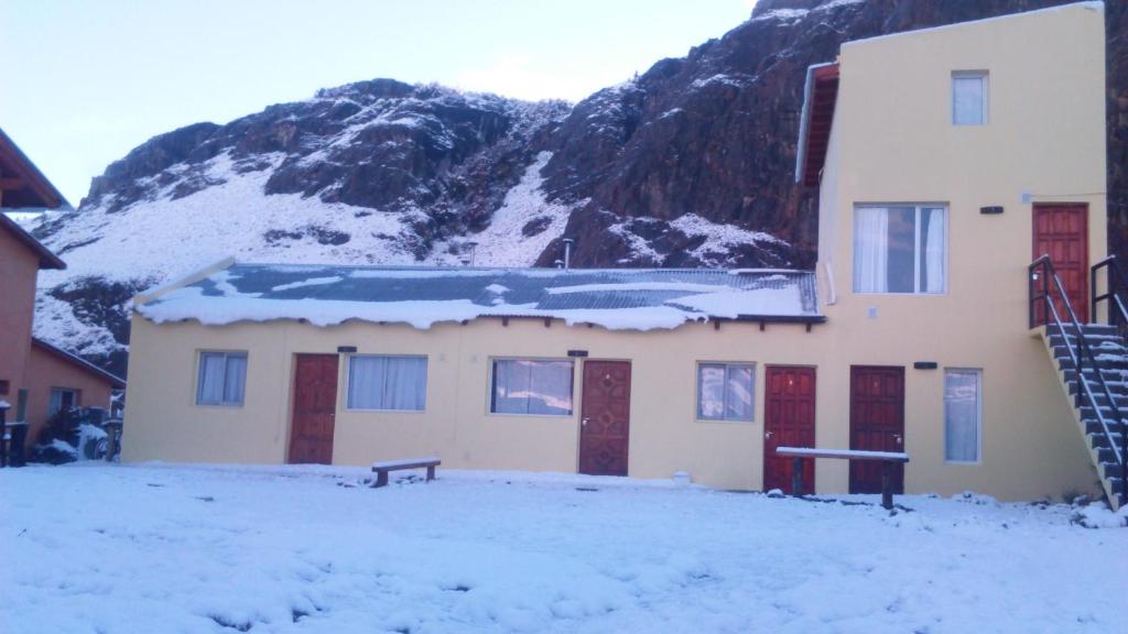 厄尔查尔坦Milenarios Hostel的山前屋顶上积雪的建筑物